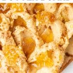 Close-up of a cinnamon honey butter board, swirled with creamy butter, drizzled with golden honey, sprinkled with ground cinnamon, and topped with chunks of honeycomb, served on a wooden board.