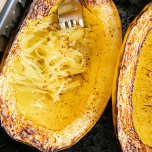 One whole cooked spaghetti squash cut in the air fryer basket cut side up.