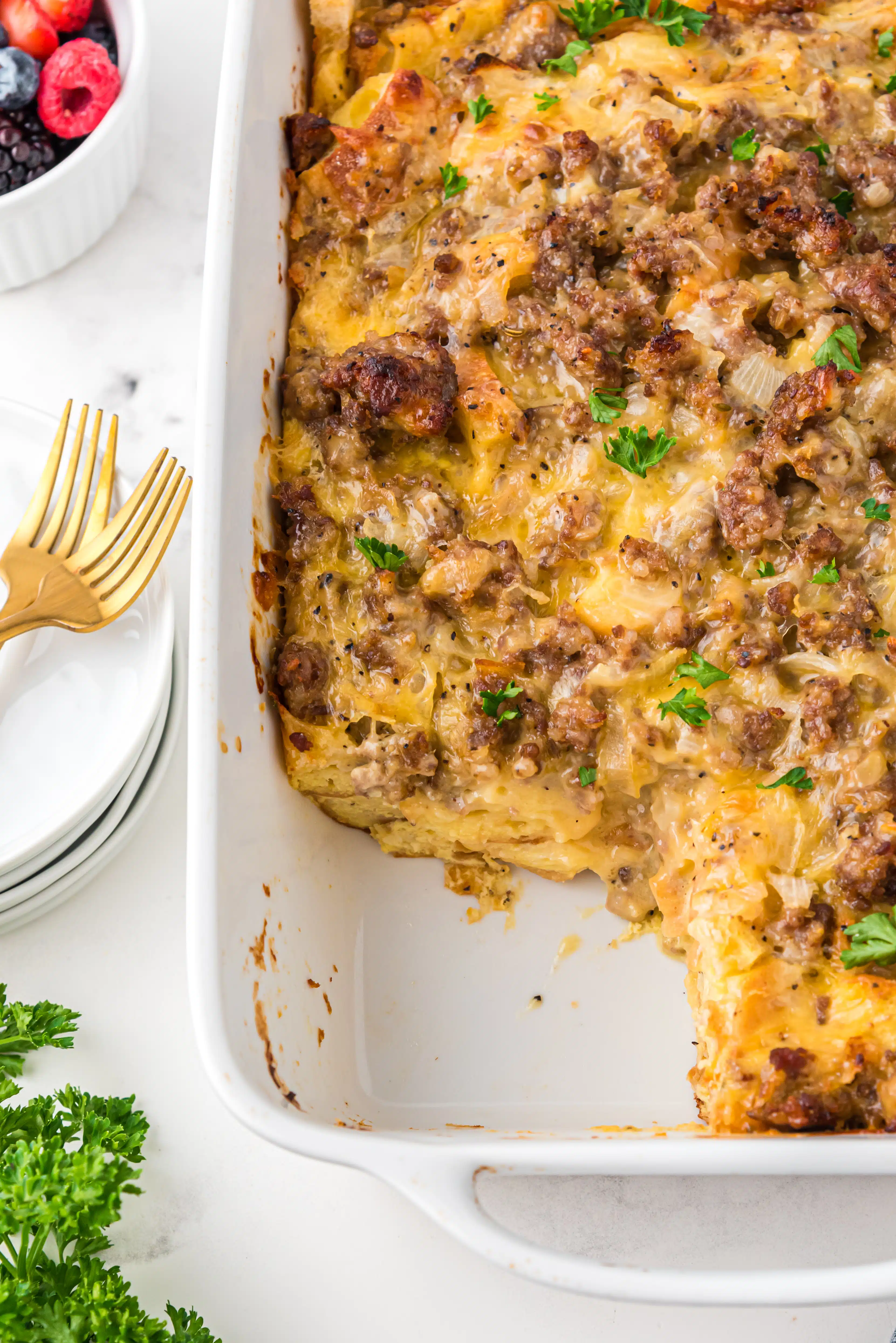 White baking dish filled with breakfast casserole made with eggs, cheese, sausage, and bread.
