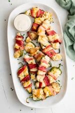 Large serving platter with Bacon Wrapped Jalapeño Poppers and a small bowl of ranch dressing.