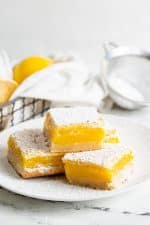 Several sliced lemon bars dusted with powdered sugar on a white plate.