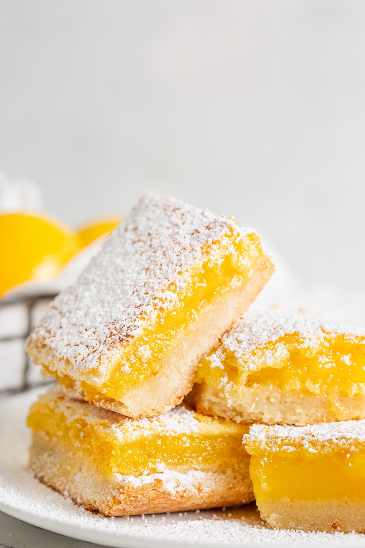 Several sliced lemon bars dusted with powdered sugar on a white plate.