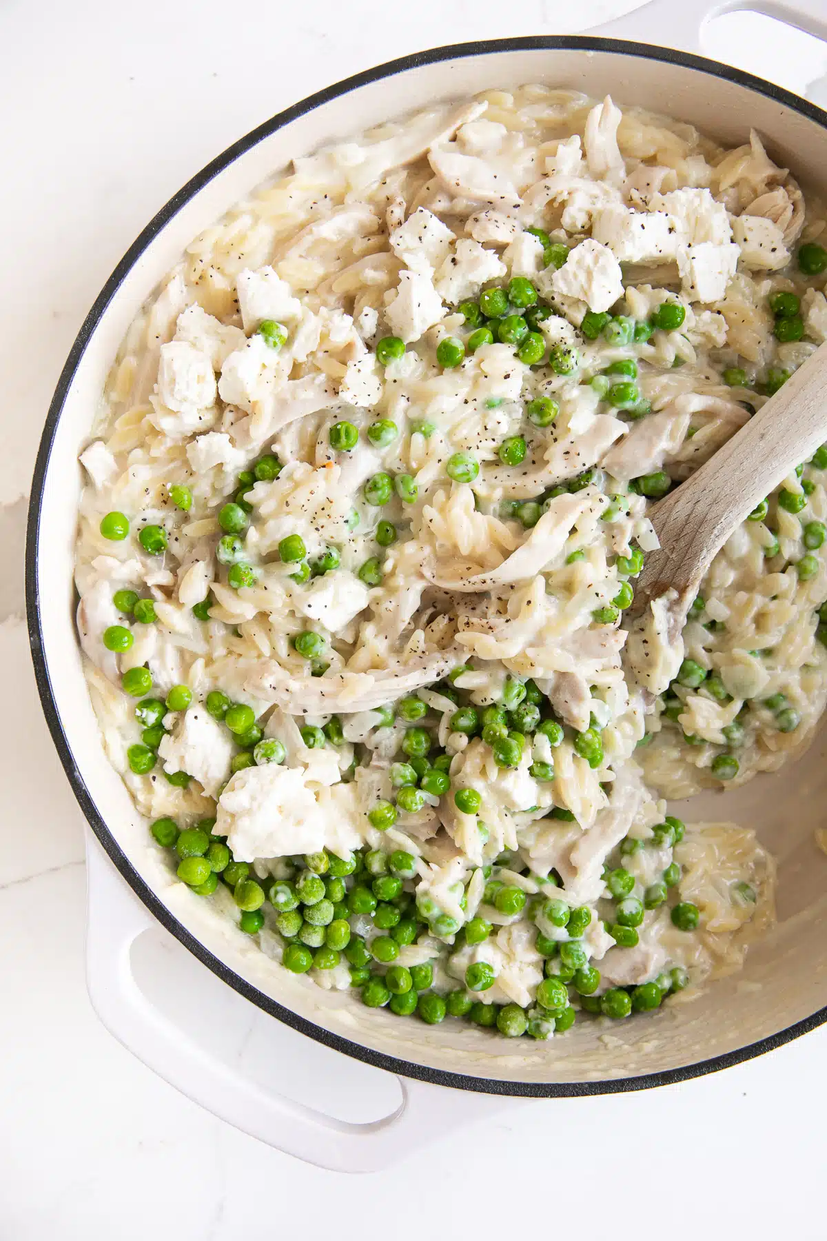 Pan filled with creamy cooked orzo made with lemon, cream, shredded chicken, peas, and feta cheese.