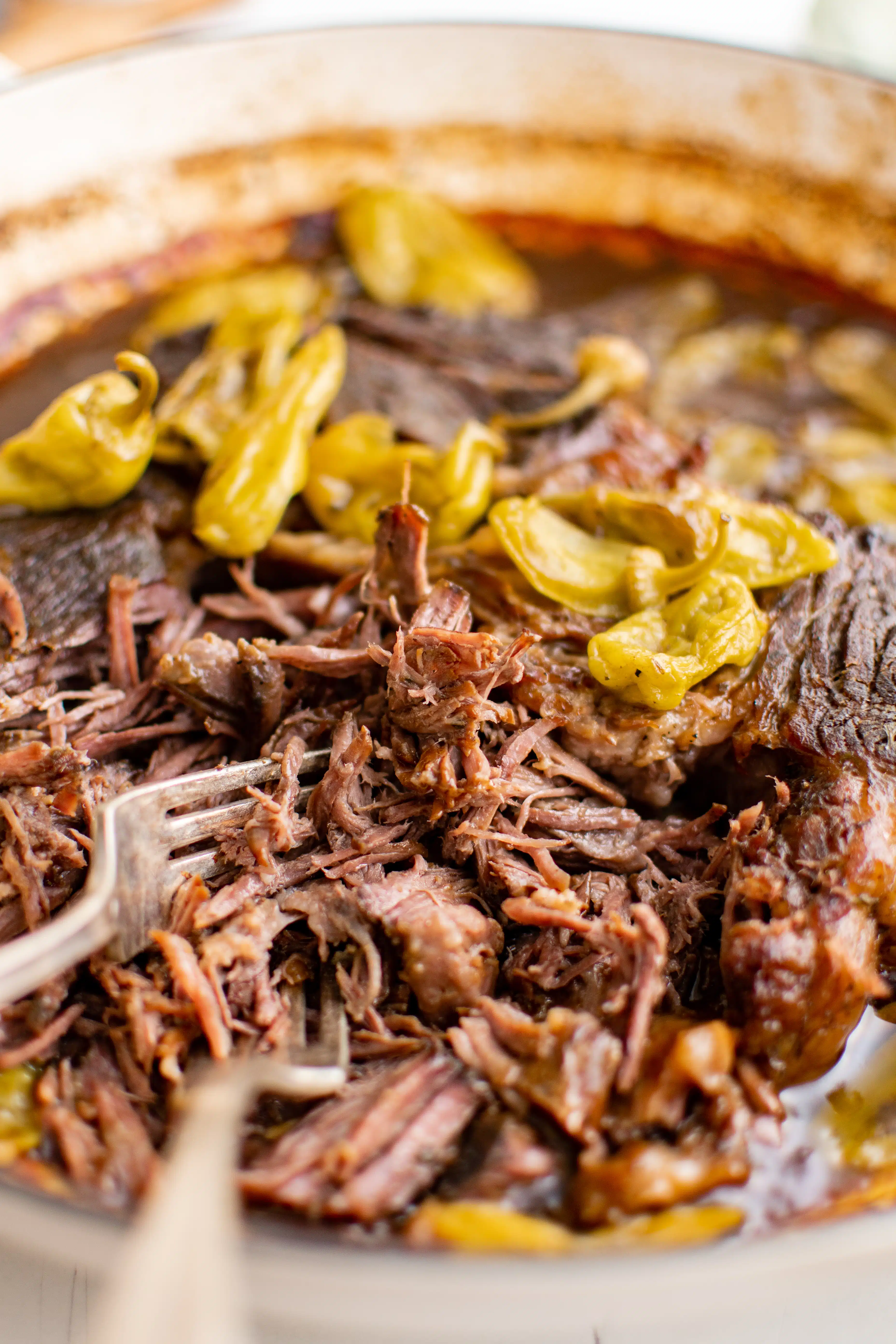 Tender cooked and shredded Mississippi pot roast in a large round Dutch oven.