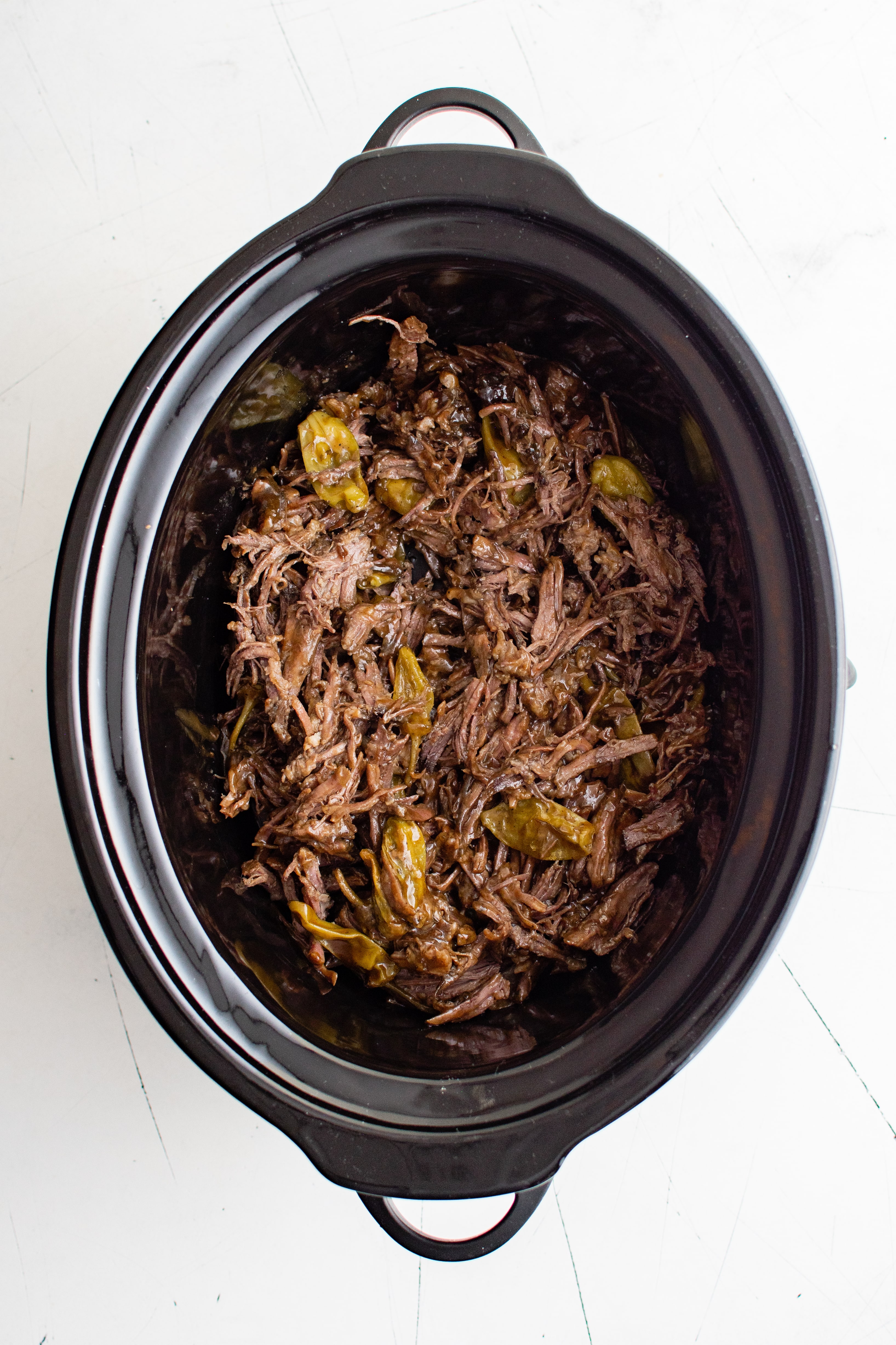 Fully cooked Mississippi pot roast in a large Crockpot.