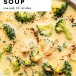 Pinterest pin featuring a close up overhead bowl of creamy broccoli cheddar soup with bright green broccoli florets, small carrot bits, and cracked black pepper on top, with a white text box in the upper left that reads โBROCCOLI CHEDDAR SOUPโ and โone-pot, 30 minutes,โ and โthe forked spoonโ text at the bottom.