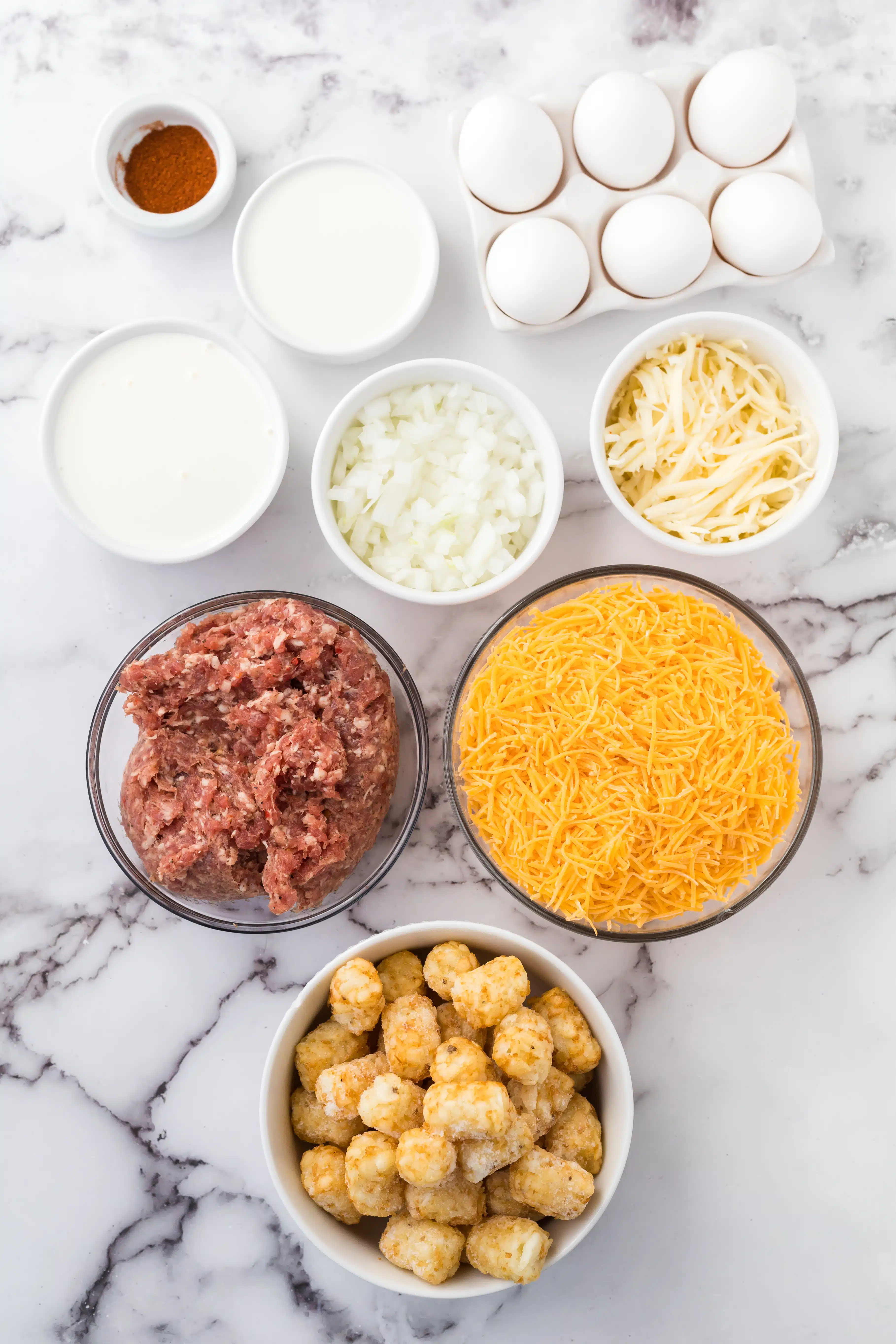 Ingredients for a breakfast casserole with tater tots set aside in individual serving bowls.