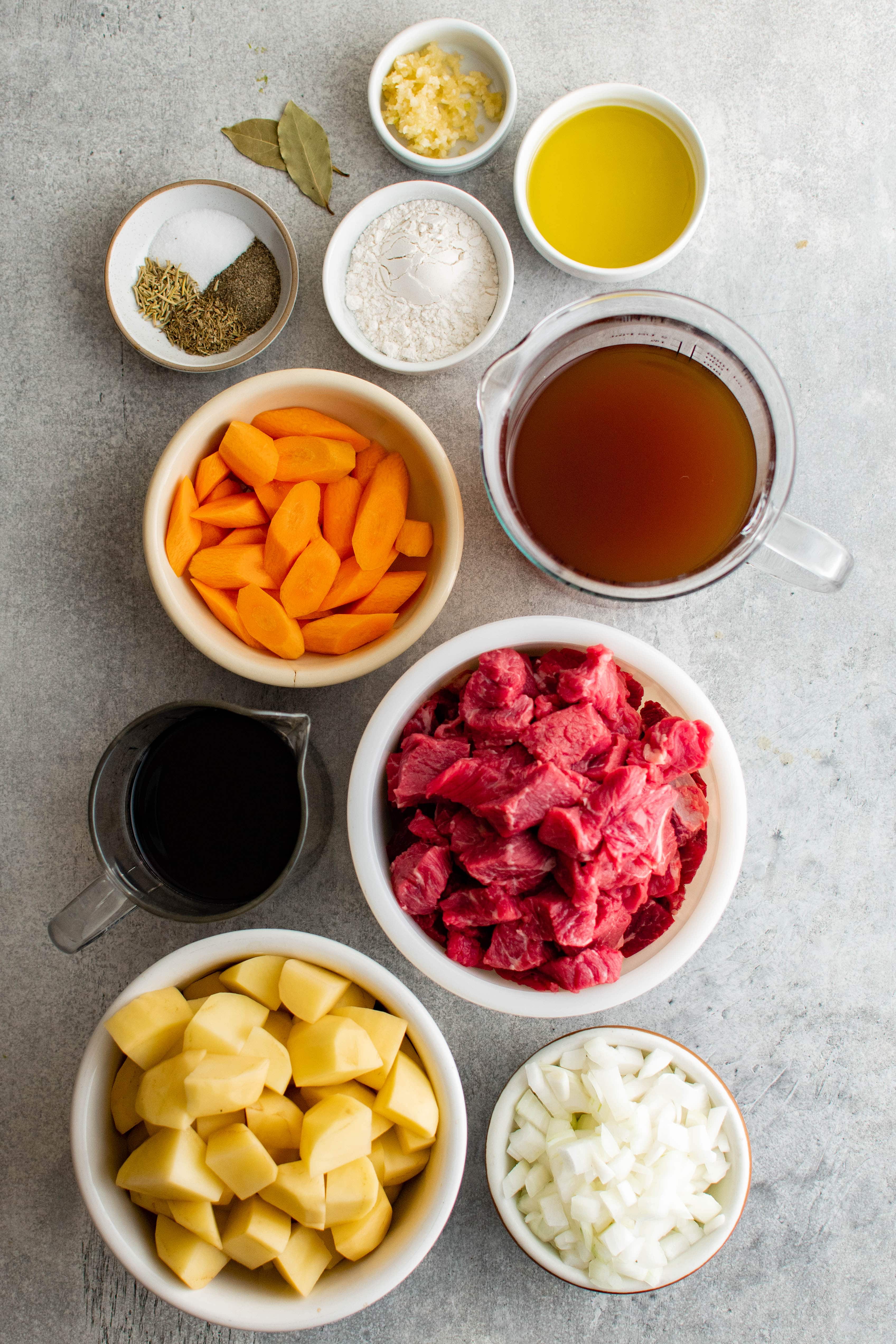 Ingredients for classic beef stew measured out and set aside in individual serving bowls.