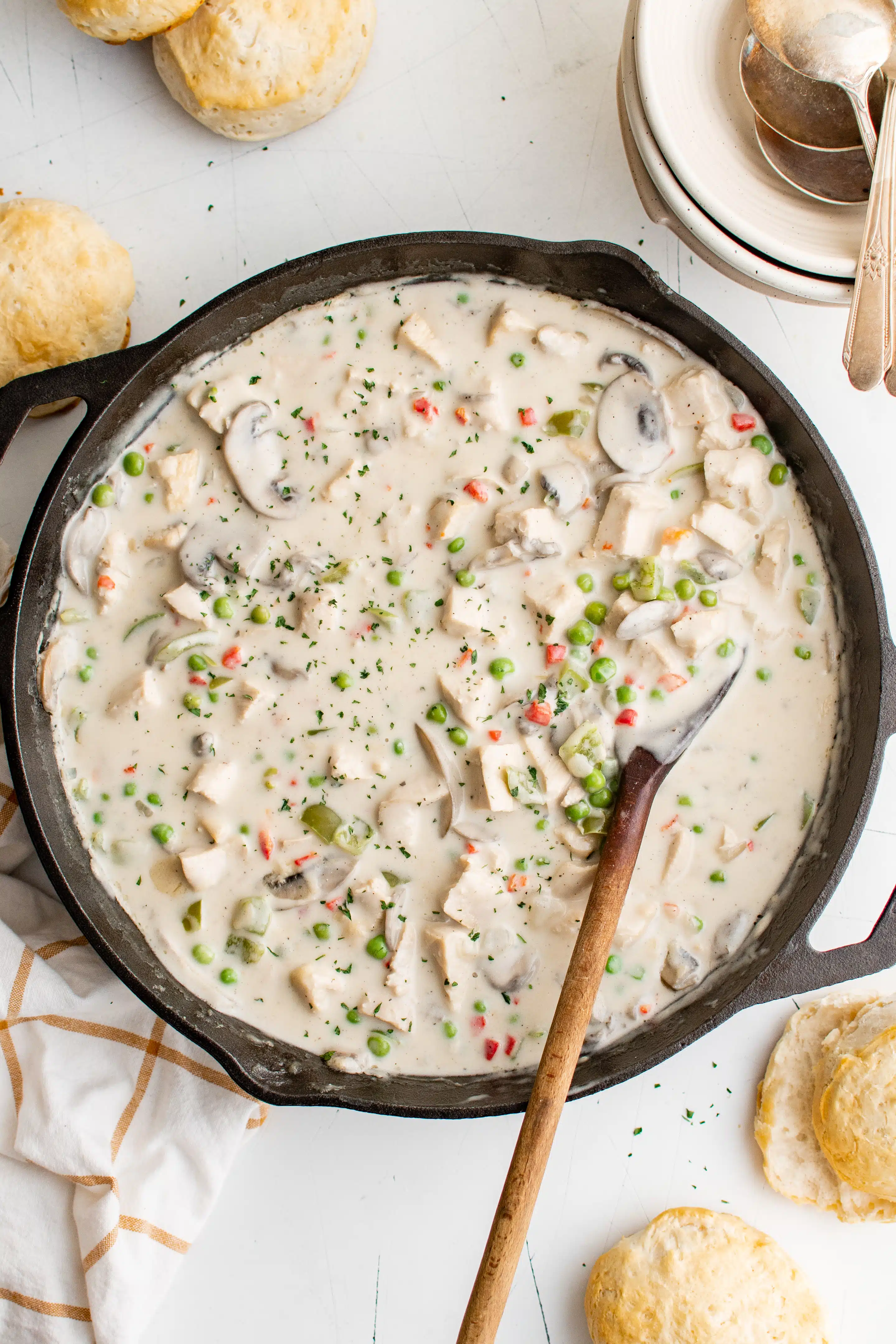 Cast iron skillet filled with creamy chicken a la king surrounded by buttermilk biscuits.