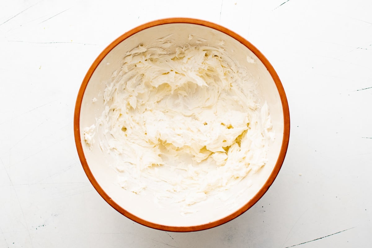 A mixing bowl filled with softened whipped cream cheese spread evenly along the sides.