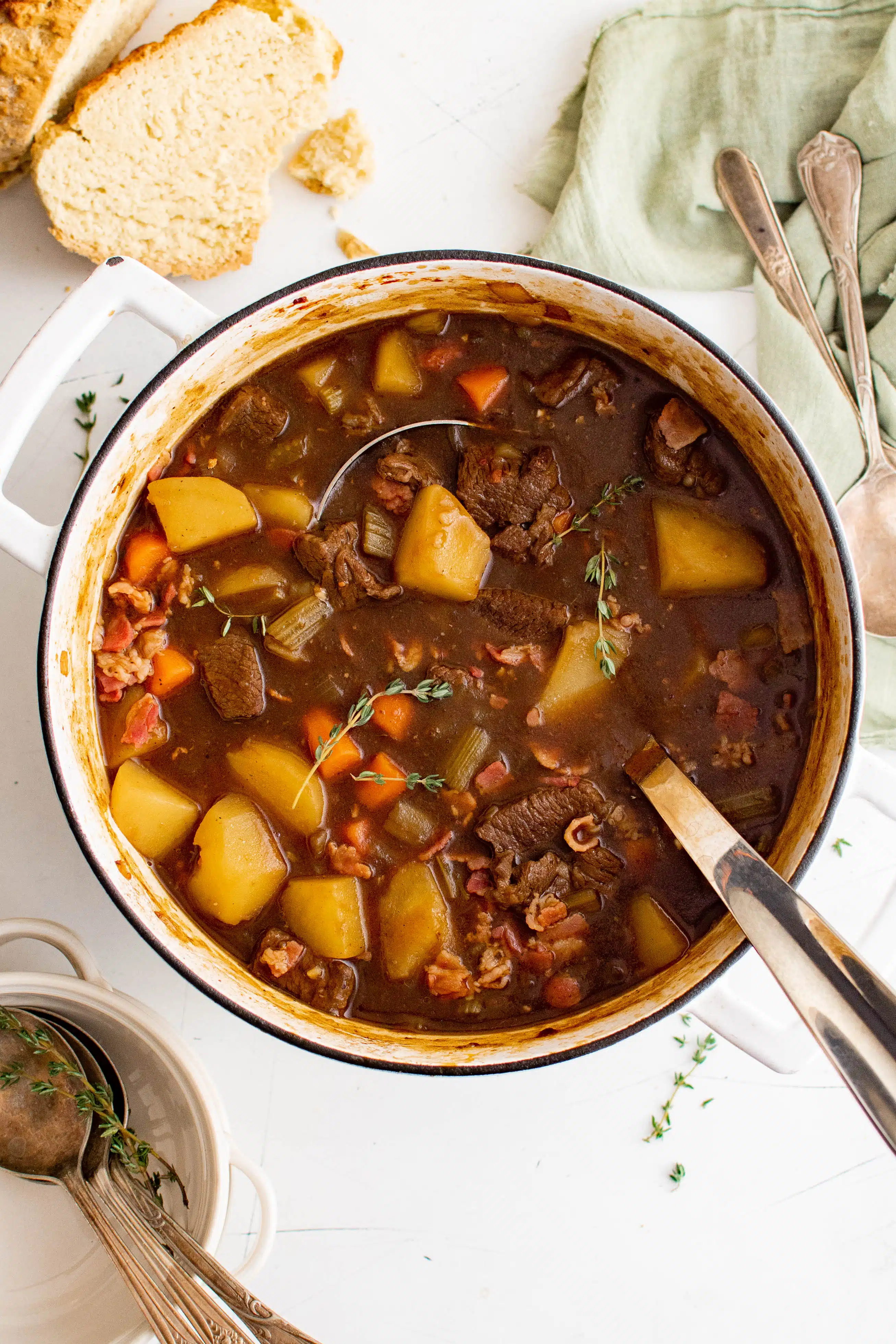 Large soup pot filled with Guinness beef stew filled with chunks of beef, potatoes, carrots, and garnished with fresh thyme.