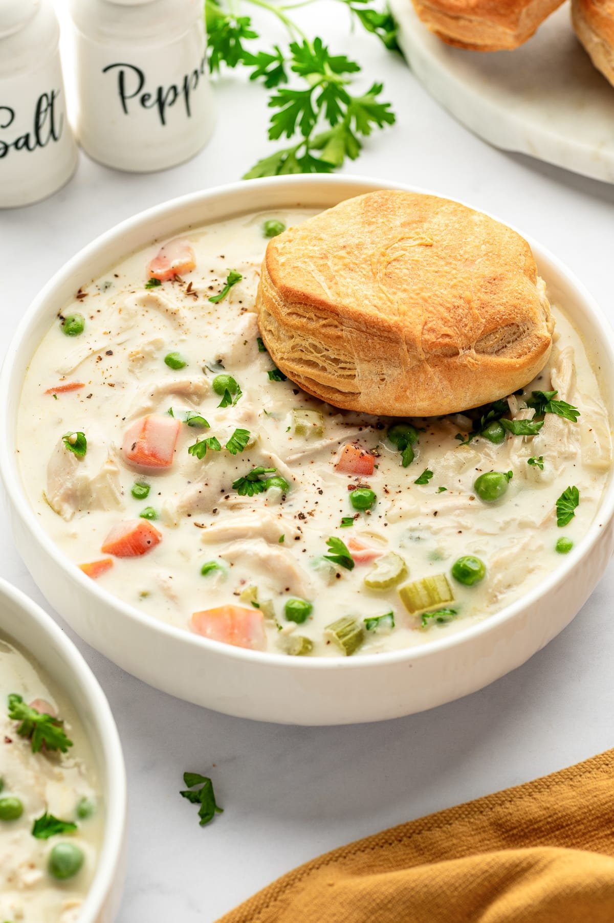Bowl of Chicken Pot Pie Soup topped with a golden, flaky buttermilk biscuit.