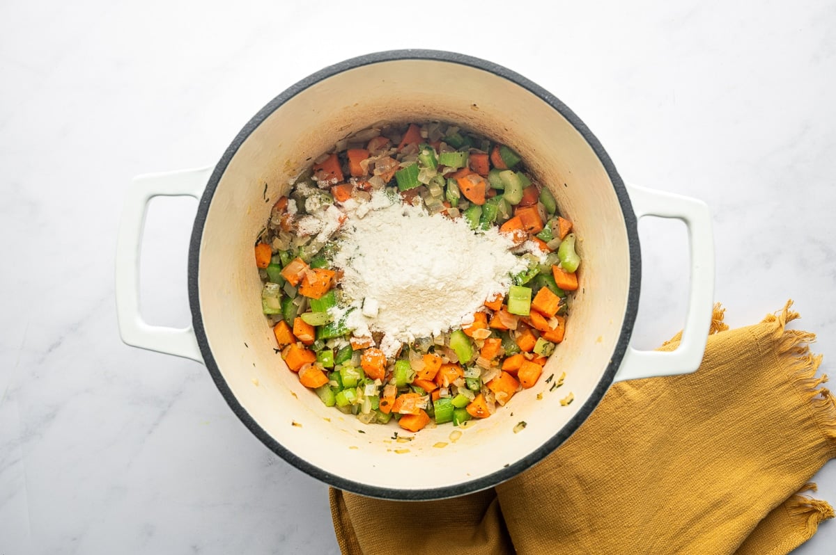 Sautéed vegetables coated with flour in a Dutch oven, forming a roux for thickening.