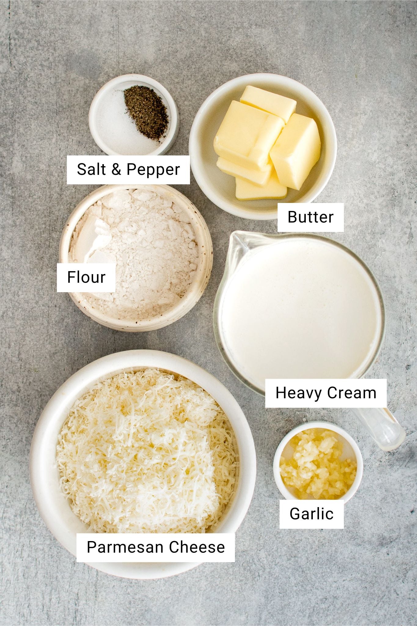 Ingredients for homemade Alfredo sauce are measured out and set aside in individual serving bowls.