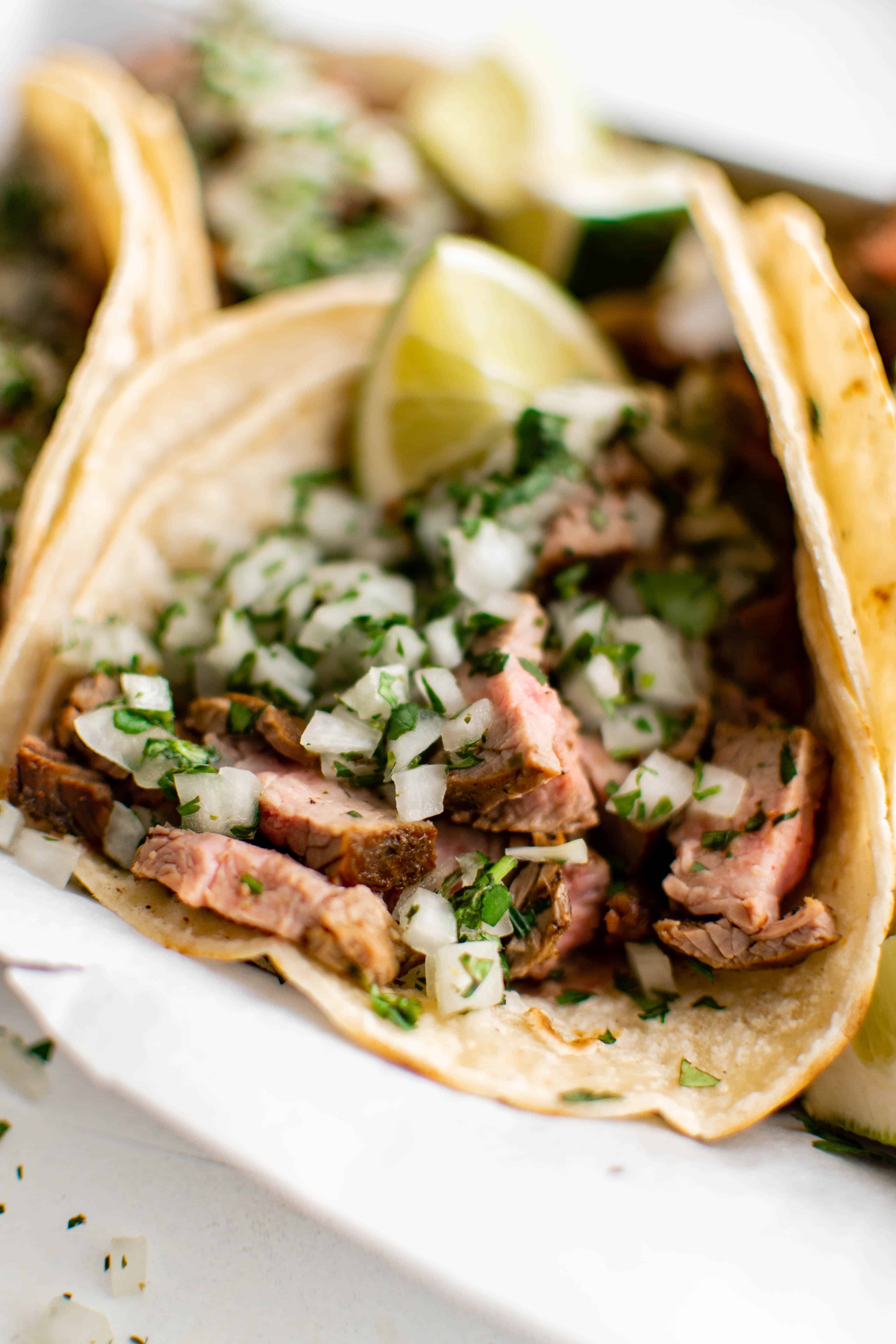 Corn tortillas filled with chopped up grilled steak and garnished with a fresh salsa made with onion, cilantro, and lime juice.