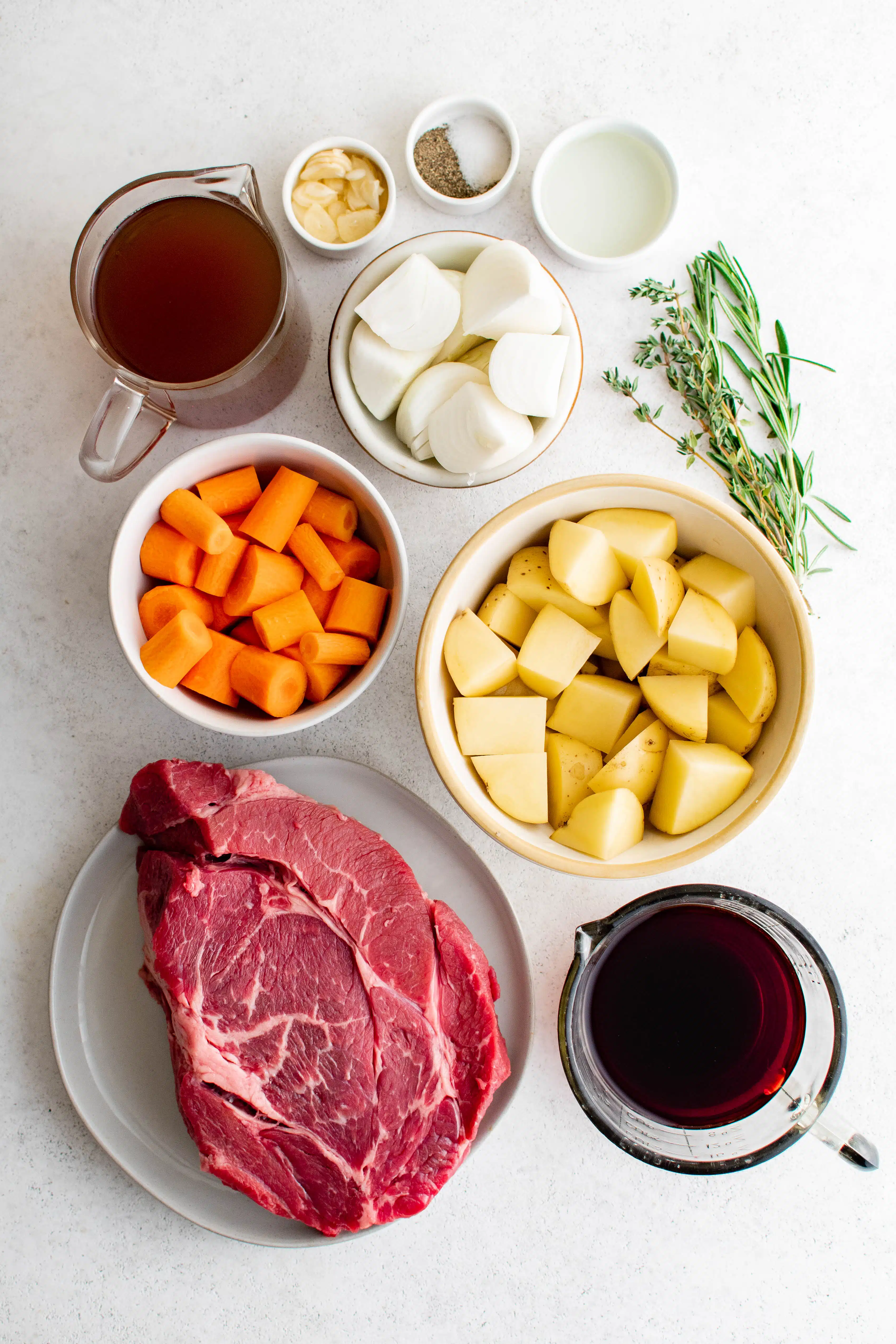 All of the ingredients needed to make Dutch Oven Pot Roast set aside in individual serving bowls.