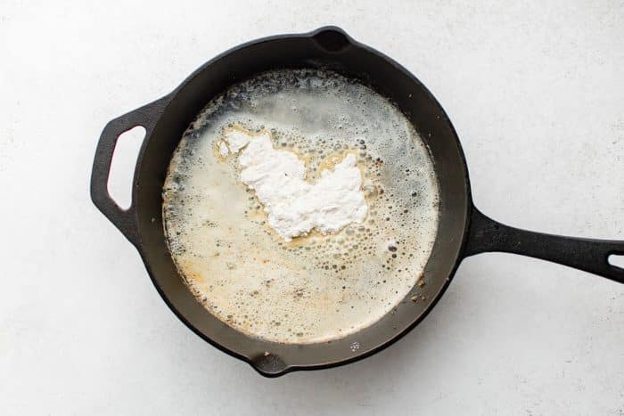 Melted butter and flour sizzling together in a cast-iron skillet to form a roux.