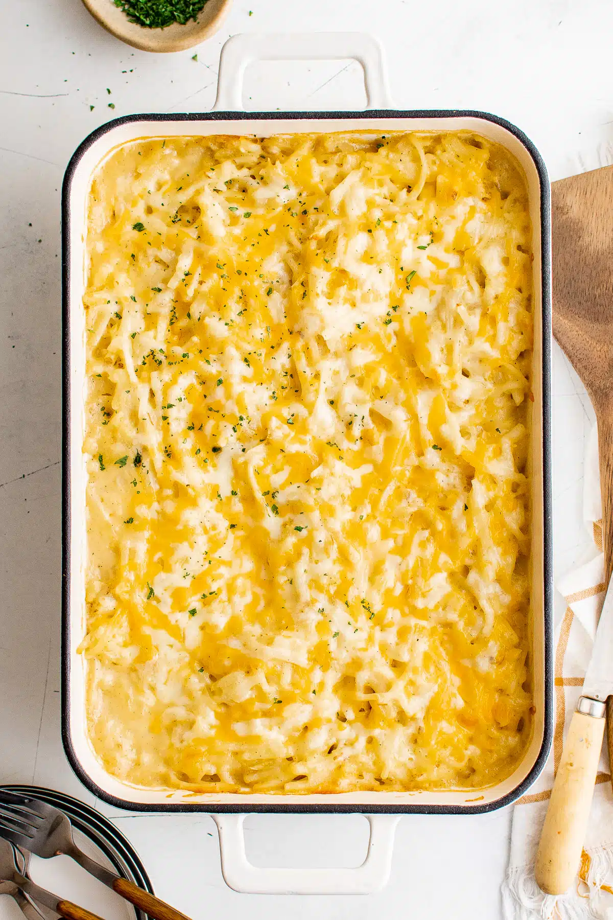 Large white baking dish filled with cheese-covered hashbrown casserole.