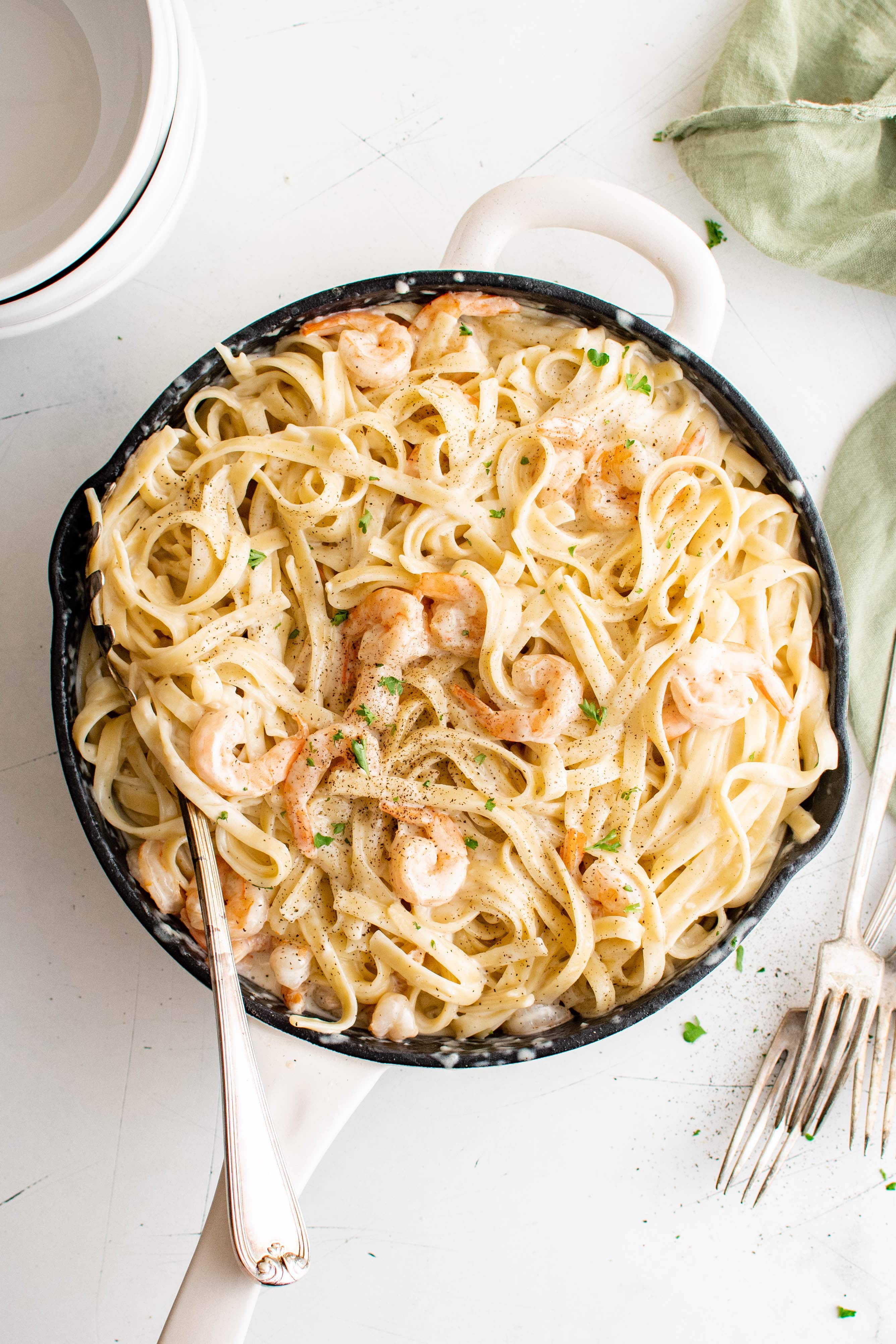 Large skillet filled with creamy shrimp alfredo with fettuccine pasta.