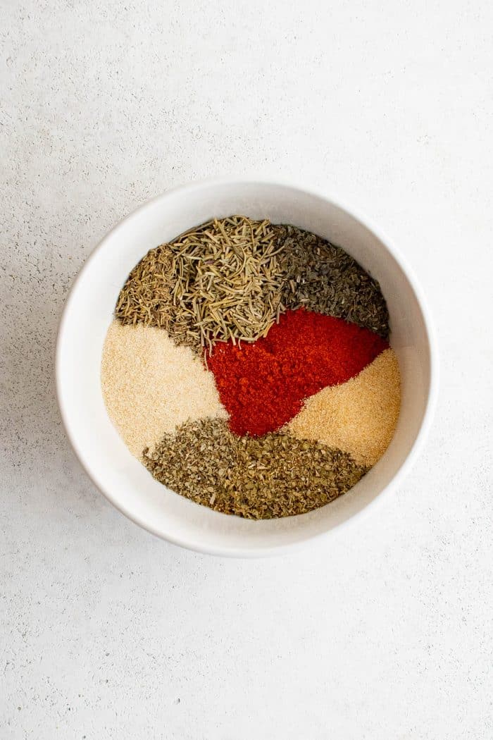 Individual spices for homemade poultry seasoning in a small white bowl.