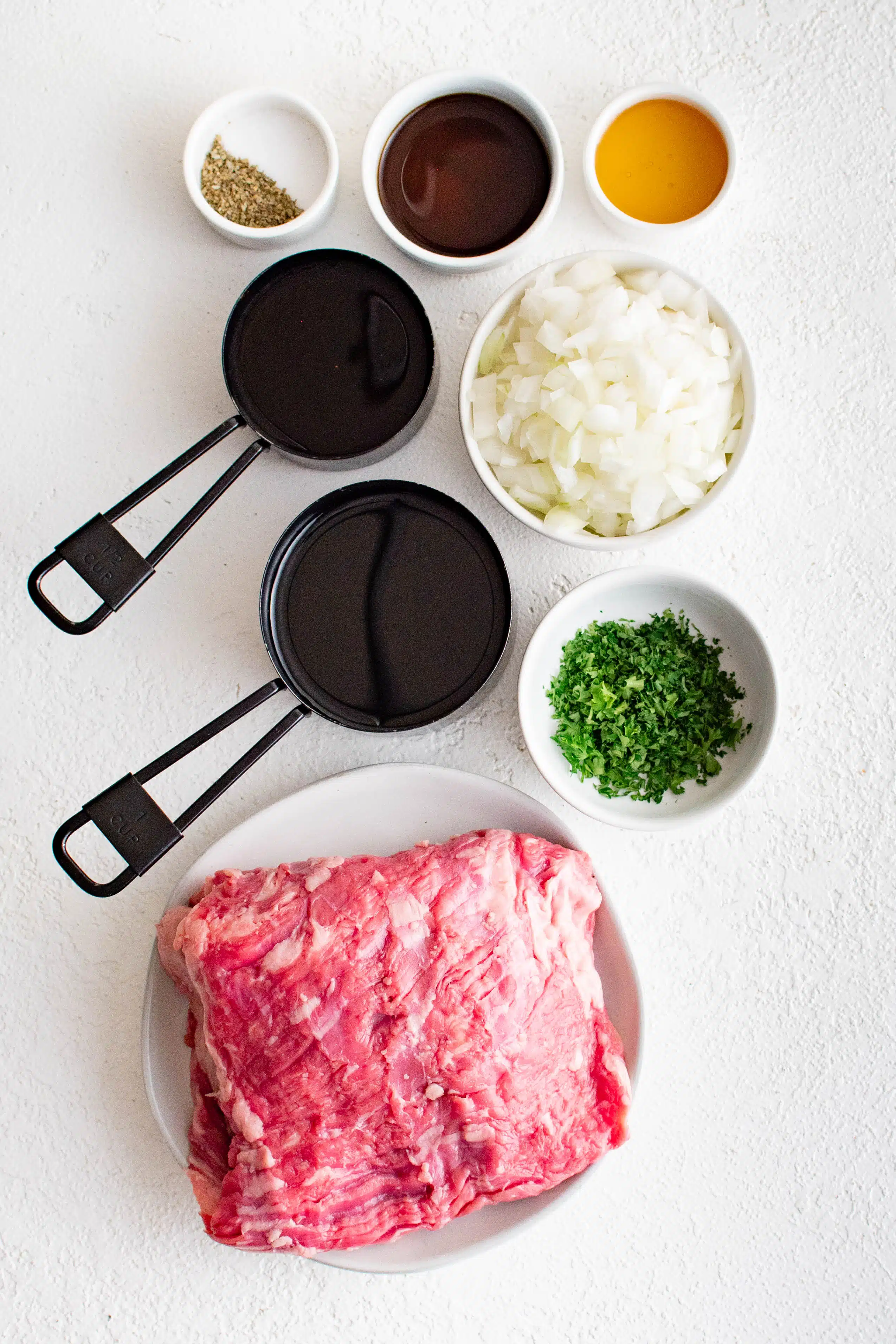 All of the ingredients to make grilled marinated skirt steak on a white table ib individual bowls.
