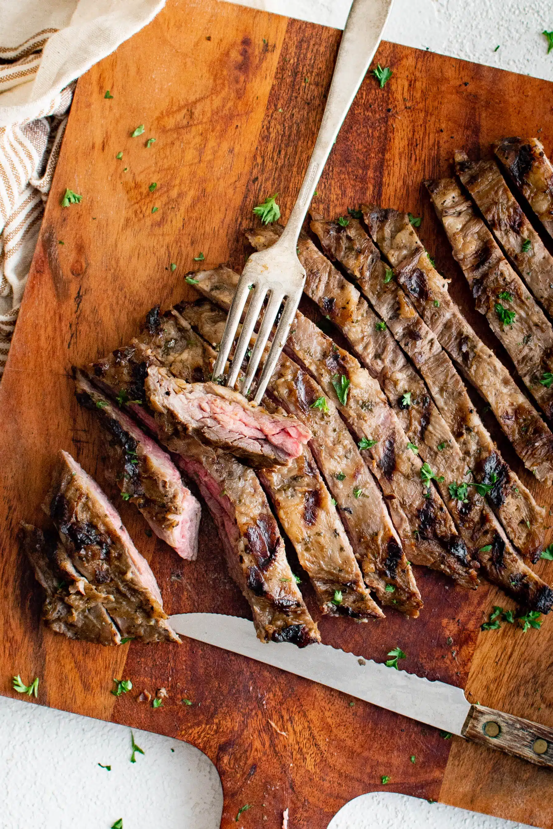 Marinated and grilled skirt steak sliced against the grain on a large cutting board.