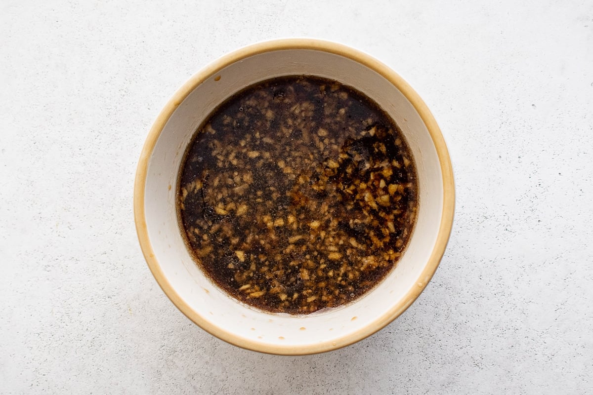 A small bowl filled with Hawaiian chicken marinade made from pineapple juice, soy sauce, garlic, ginger, and brown sugar.