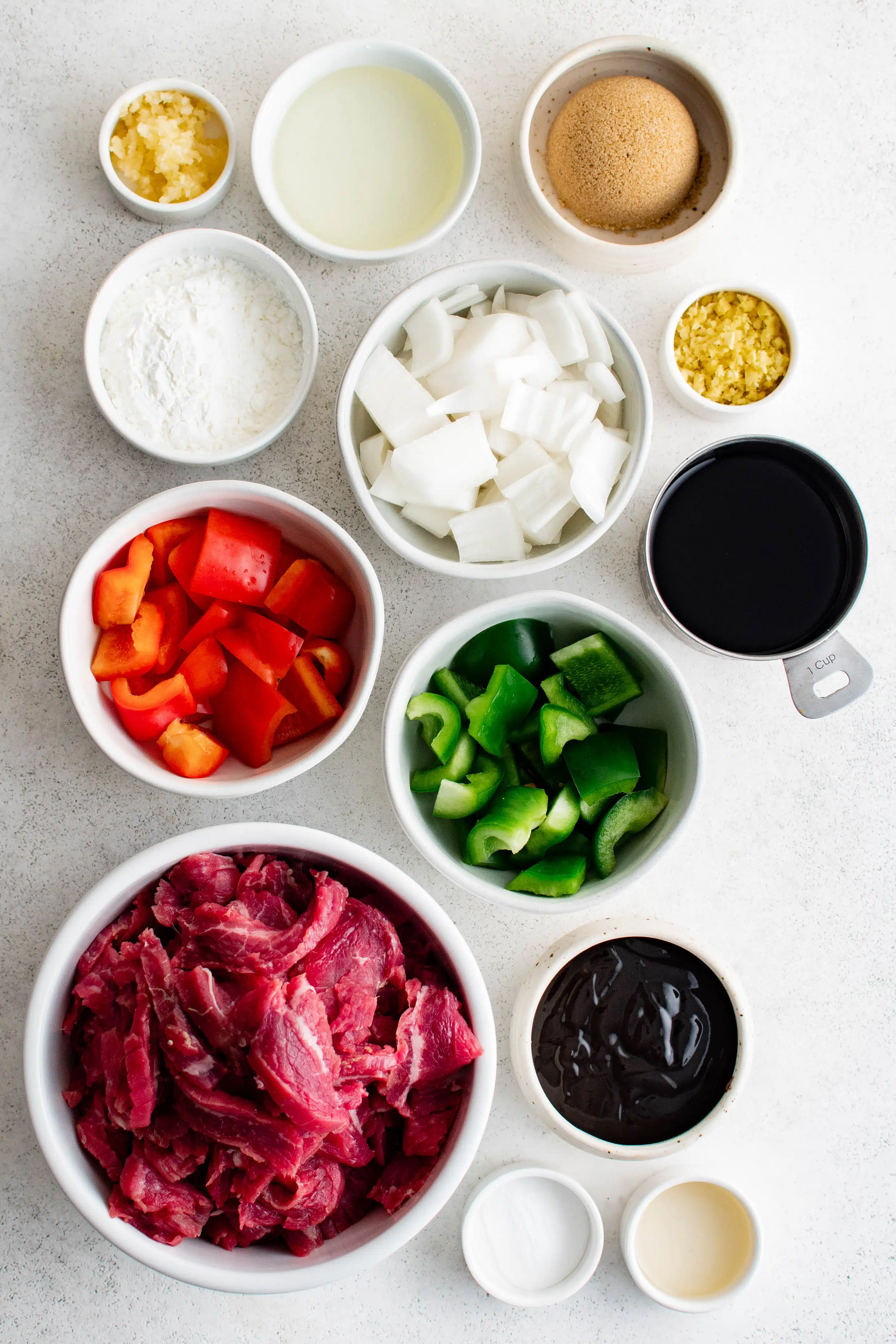 All of the ingredients required to make Mongolian beef set aside in individual serving dishes.