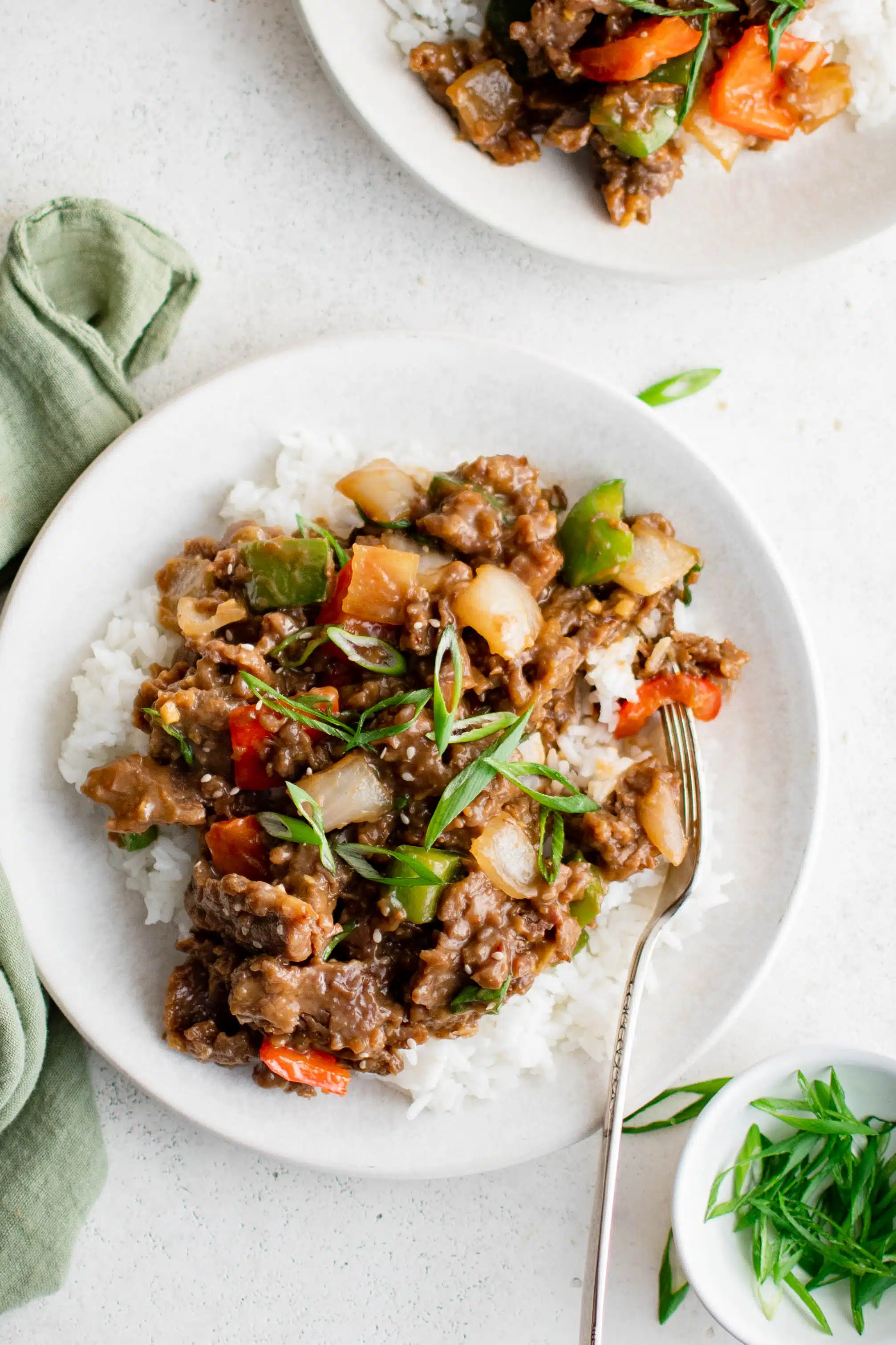Cooked Mongolian Beef with red and green bell peppers served atop a bed of cooked white rice.