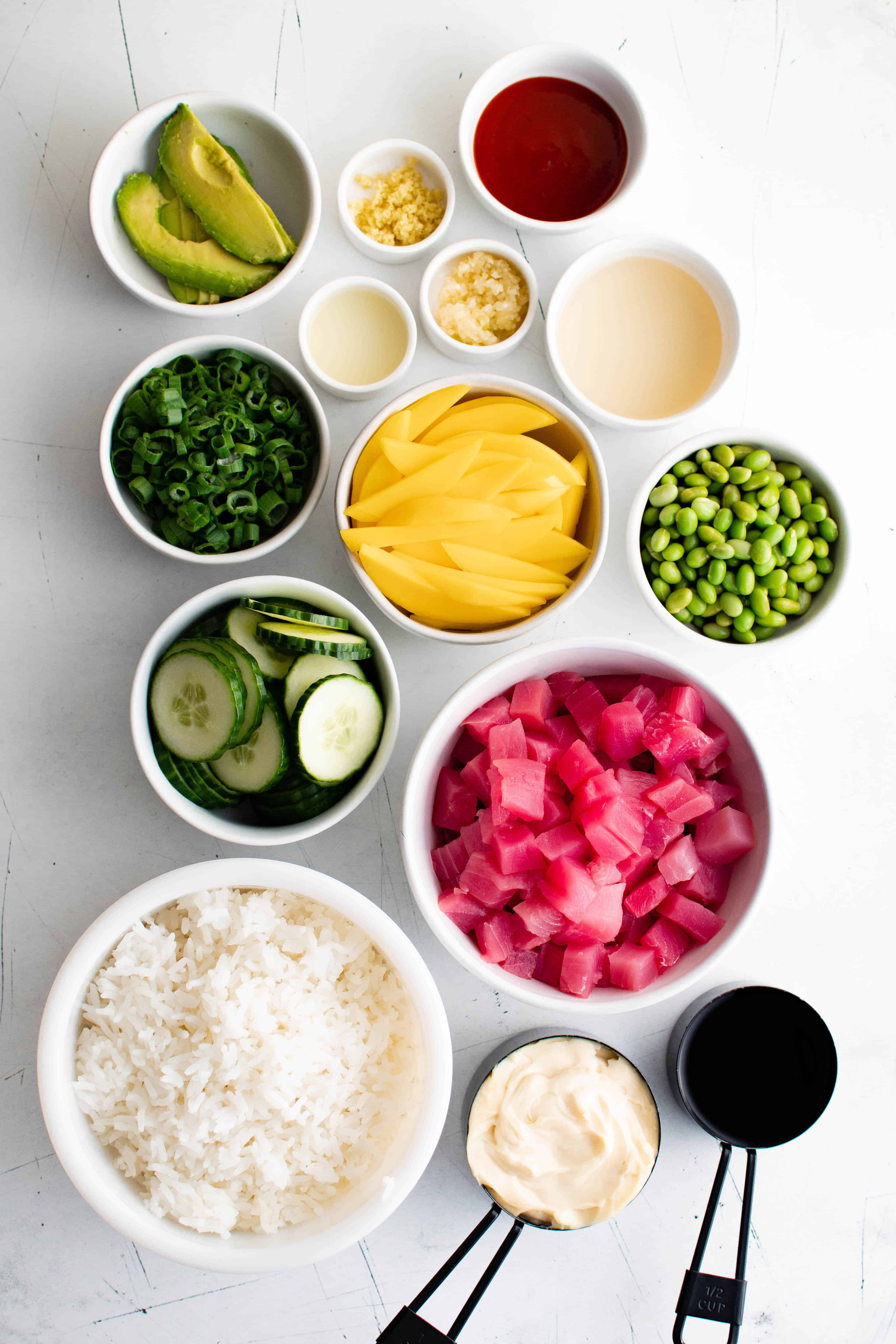 All of the ingredients in separate individual bowls and dishes to make poke bowls.