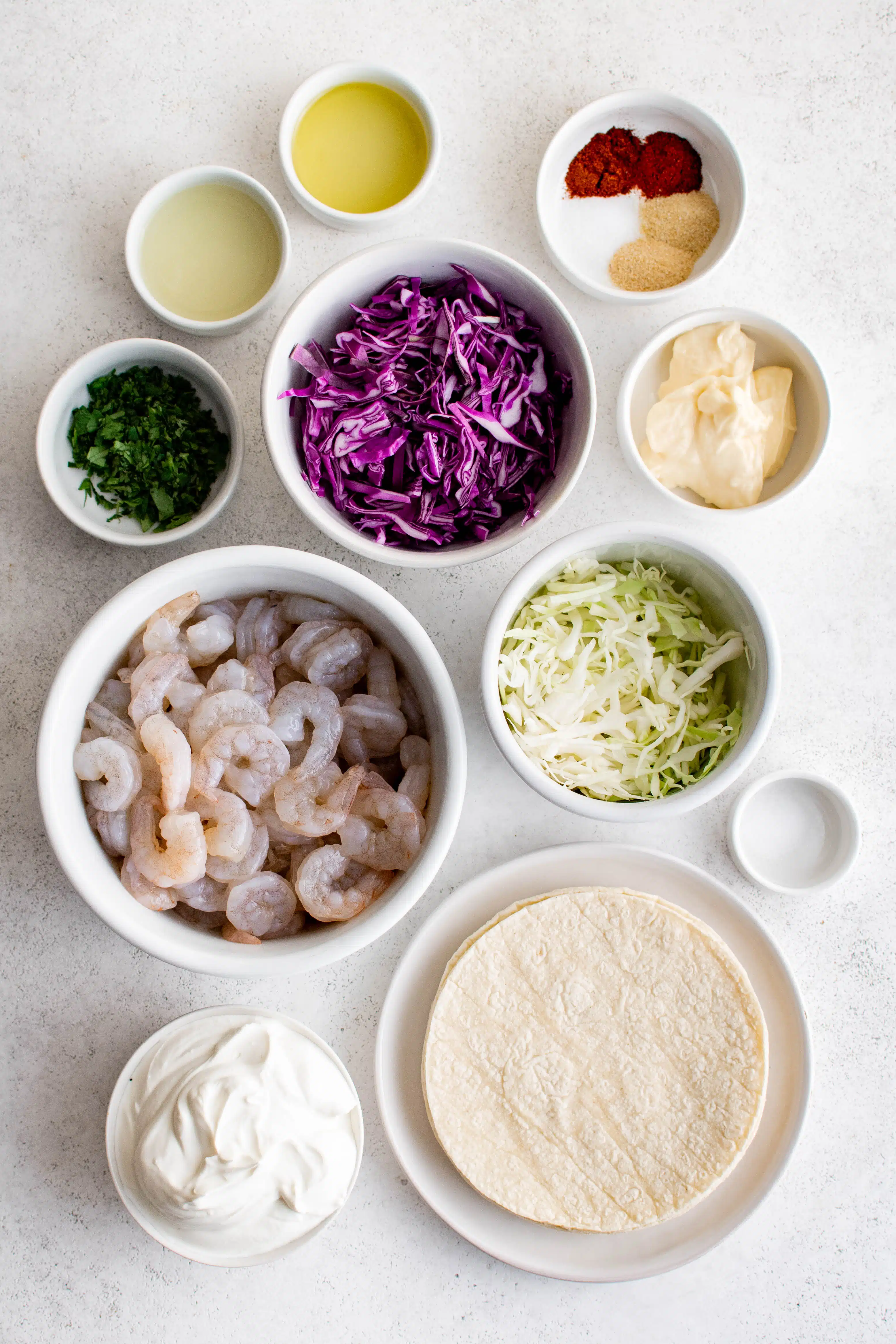 Ingredients to make shrimp tacos set aside in individual serving bowls.