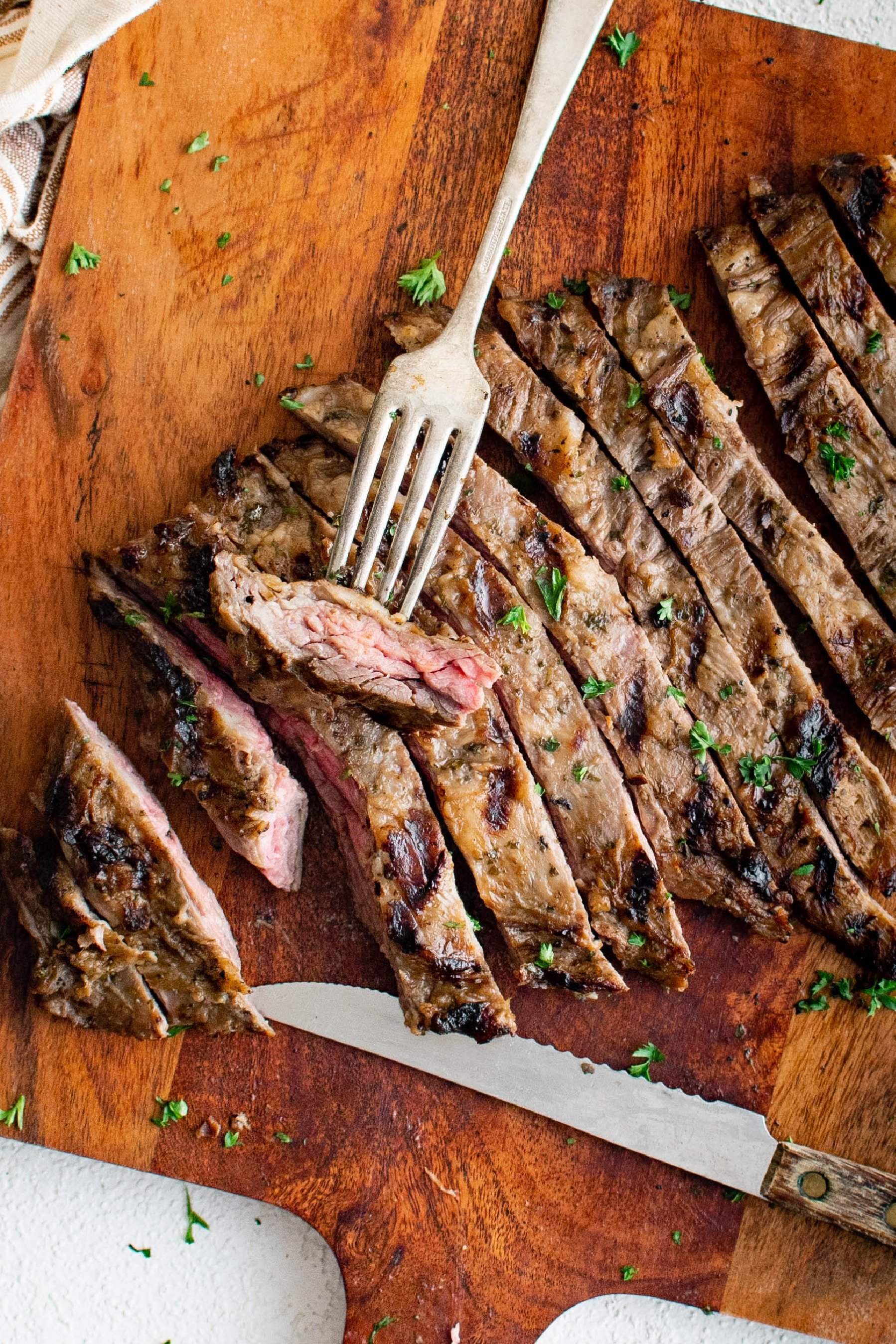 Marinated and grilled skirt steak sliced against the grain on a large cutting board.