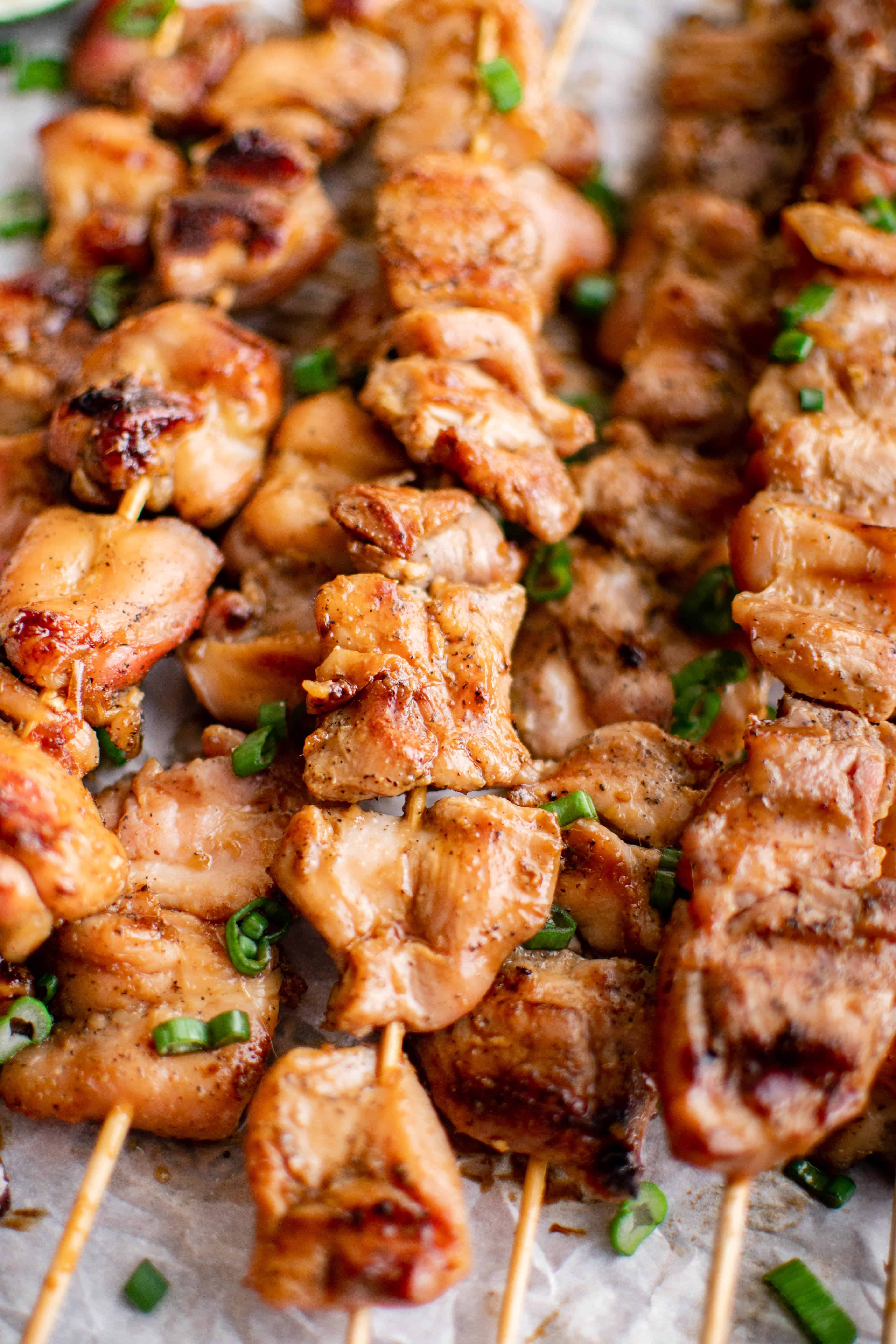 stack of cooked chicken Yakitori skewers garnished with sliced green onions.