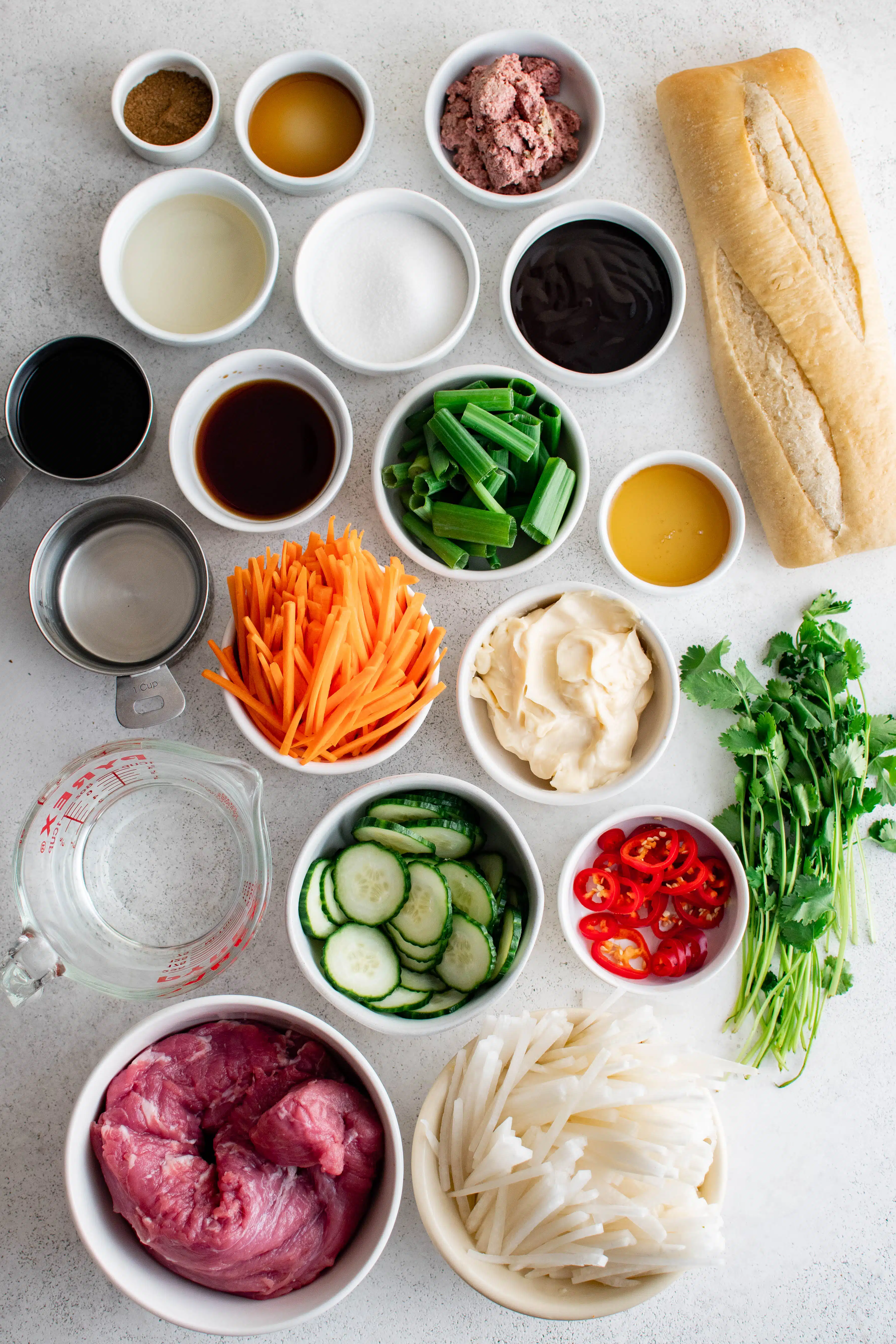 All of the ingredients needed to make Bánh Mì measured and set aside in individual white bowls.