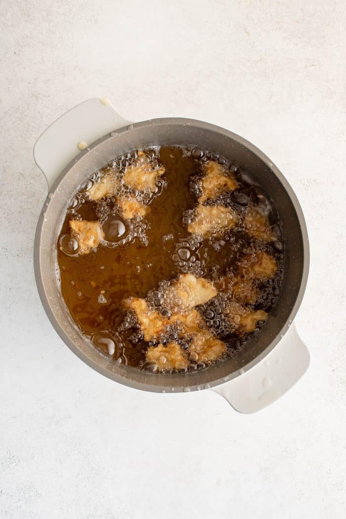 Chicken pieces double frying in a large Dutch oven.