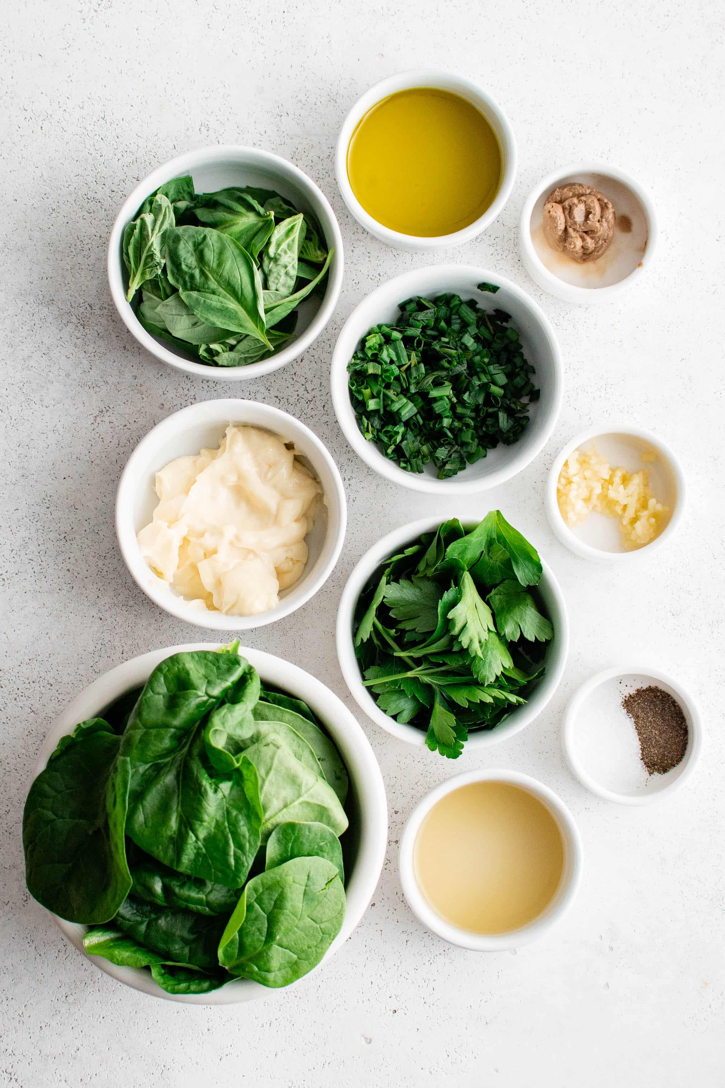 Ingredients needed to make green goddess dressing in individual measuring cups and ramekins.