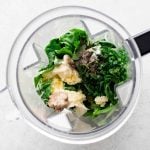 All of the ingredients needed to make homemade green goddess dressing in the bowl of a blender.