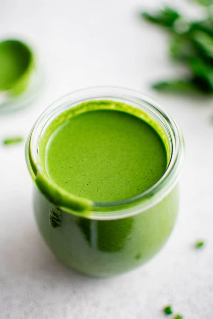 Overhead image of a small glass jar filled with homemade green goddess dressing.