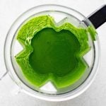 Beautiful emerald colored homemade green goddess dressing in the bowl of a blender.