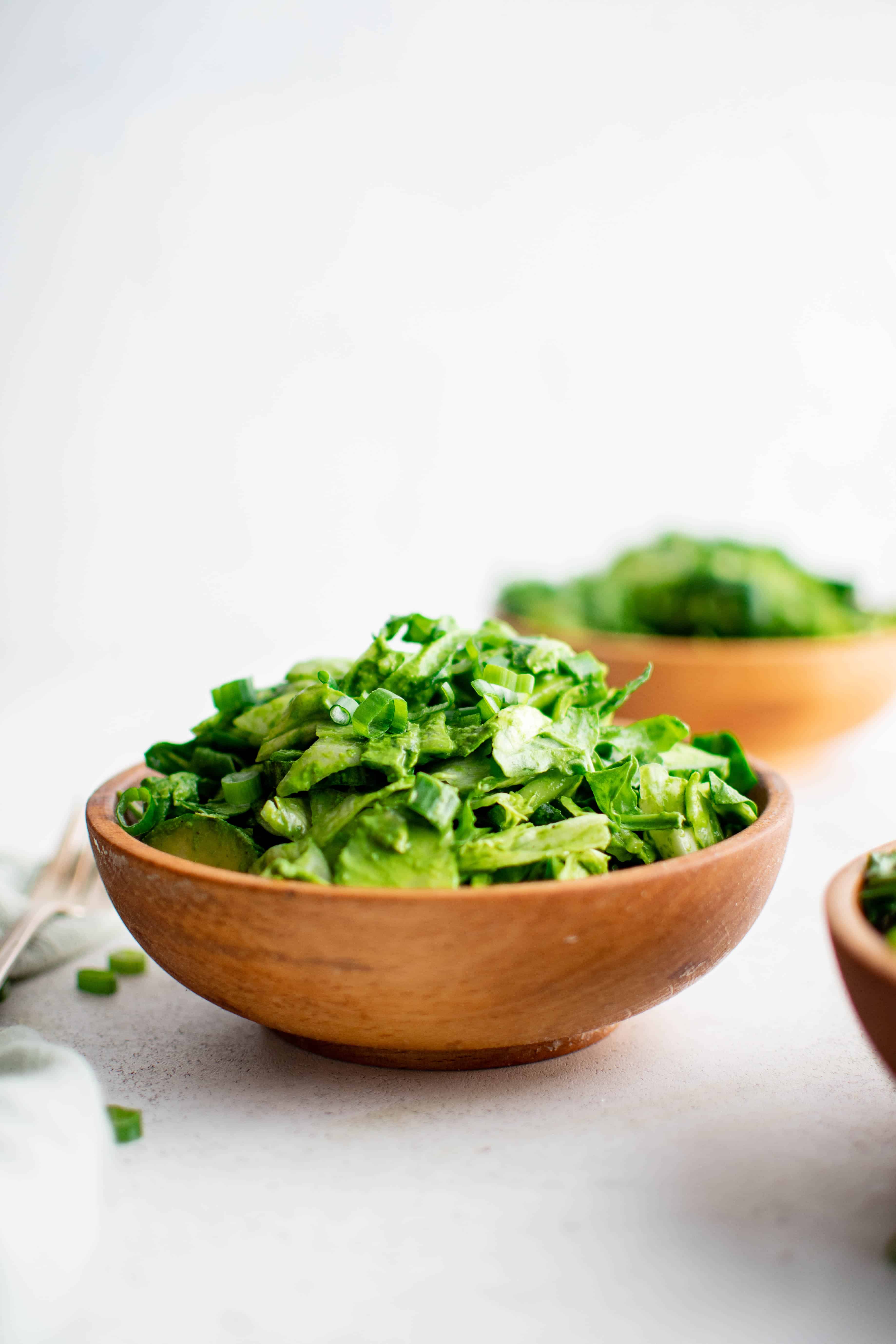 Small wood salad bowl filled with fresh and light green goddess salad.