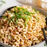 Large, shallow serving bowl filled Hawaiian macaroni salad and garnished with fresh green onions.