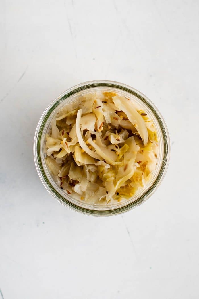 Overhead image of a glass jar filled with homemade sauerkraut.