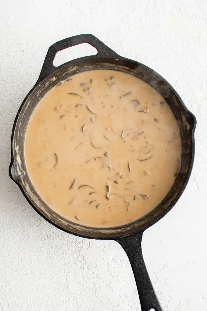 Jägerschnitzel sauce simmering in a cast iron pan.