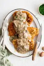 Large platter filled with four breaded and fried pork cutlets smothered in a bacon mushroom cream sauce and garnished with freshly minced parsley.