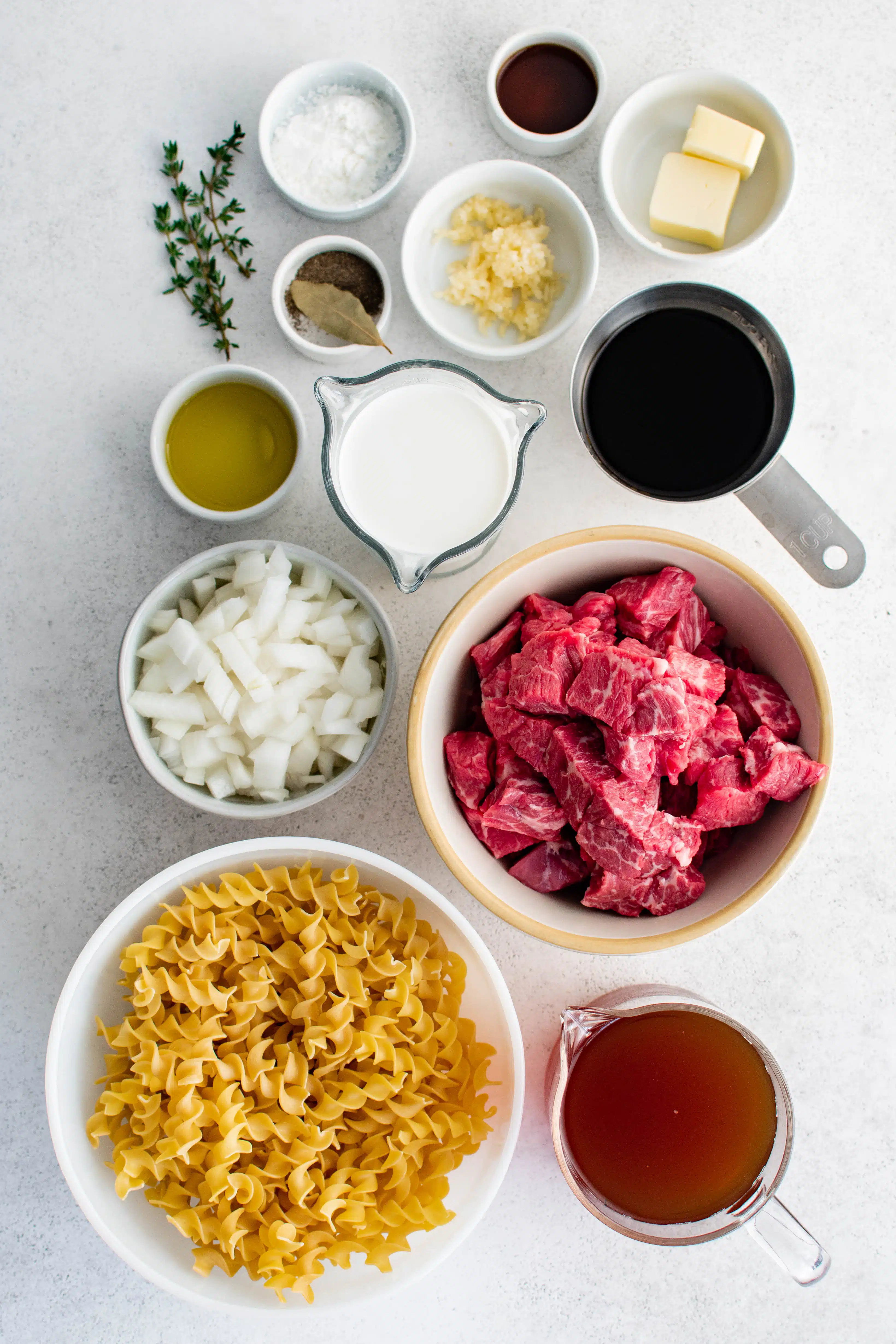 Ingredients needed to make beef and noodles recipe in individual measuring cups and ramekins.