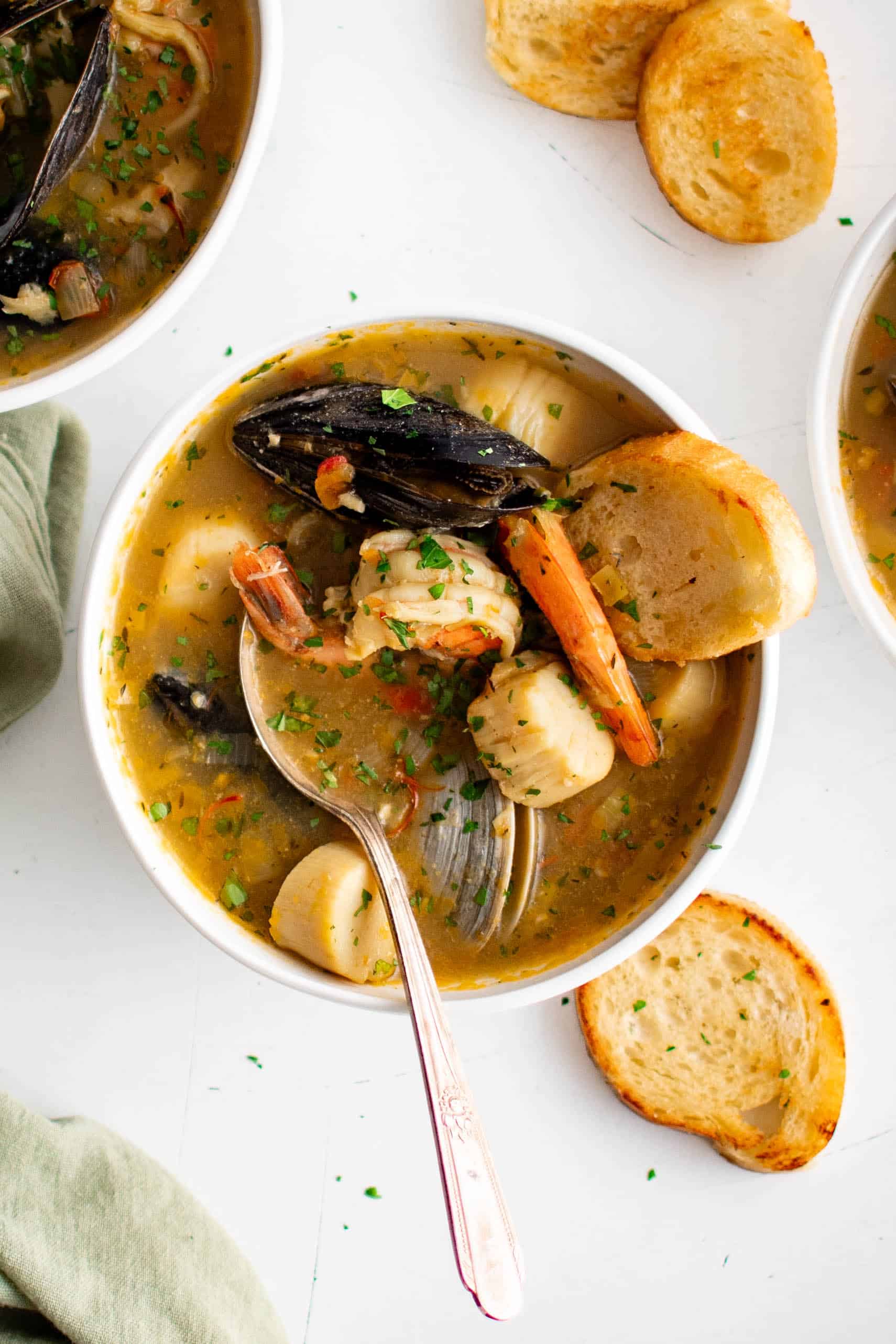 Overhead image of one white bowls filled with bouillabaisse, a French soup made with fish and fresh seafood.