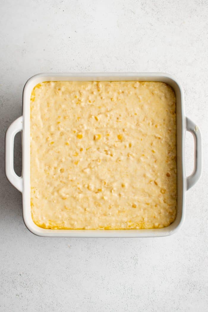 White 9-by-9 inch baking dish filled with Jiffy cornbread casserole mixture.