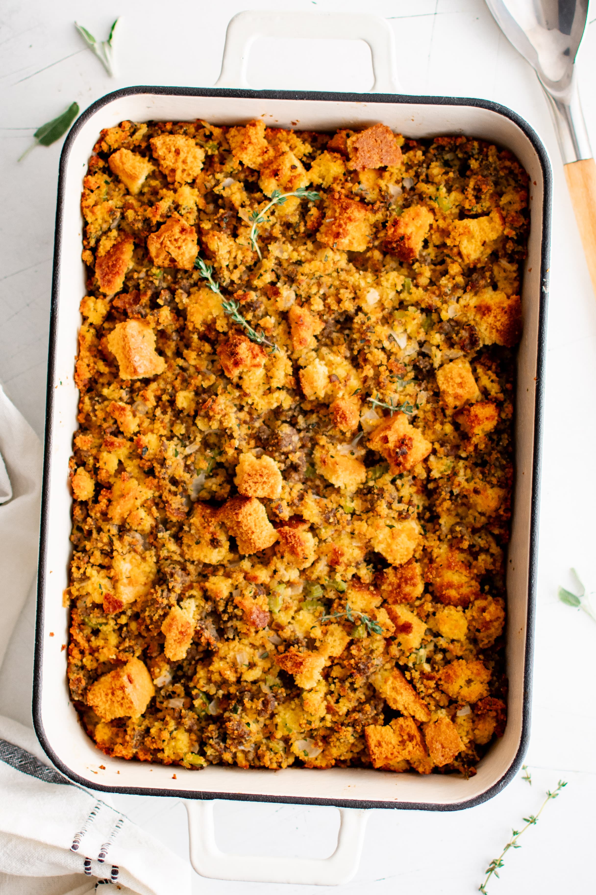 Overhead image of a large rectangle baking dish filled with cornbread dressing with sausage and fresh herbs.