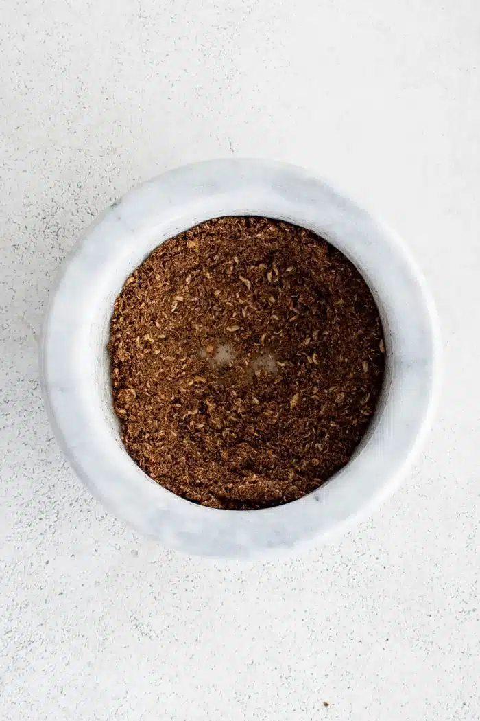 Mortar and pestle filled with ground sichuan peppercorns.