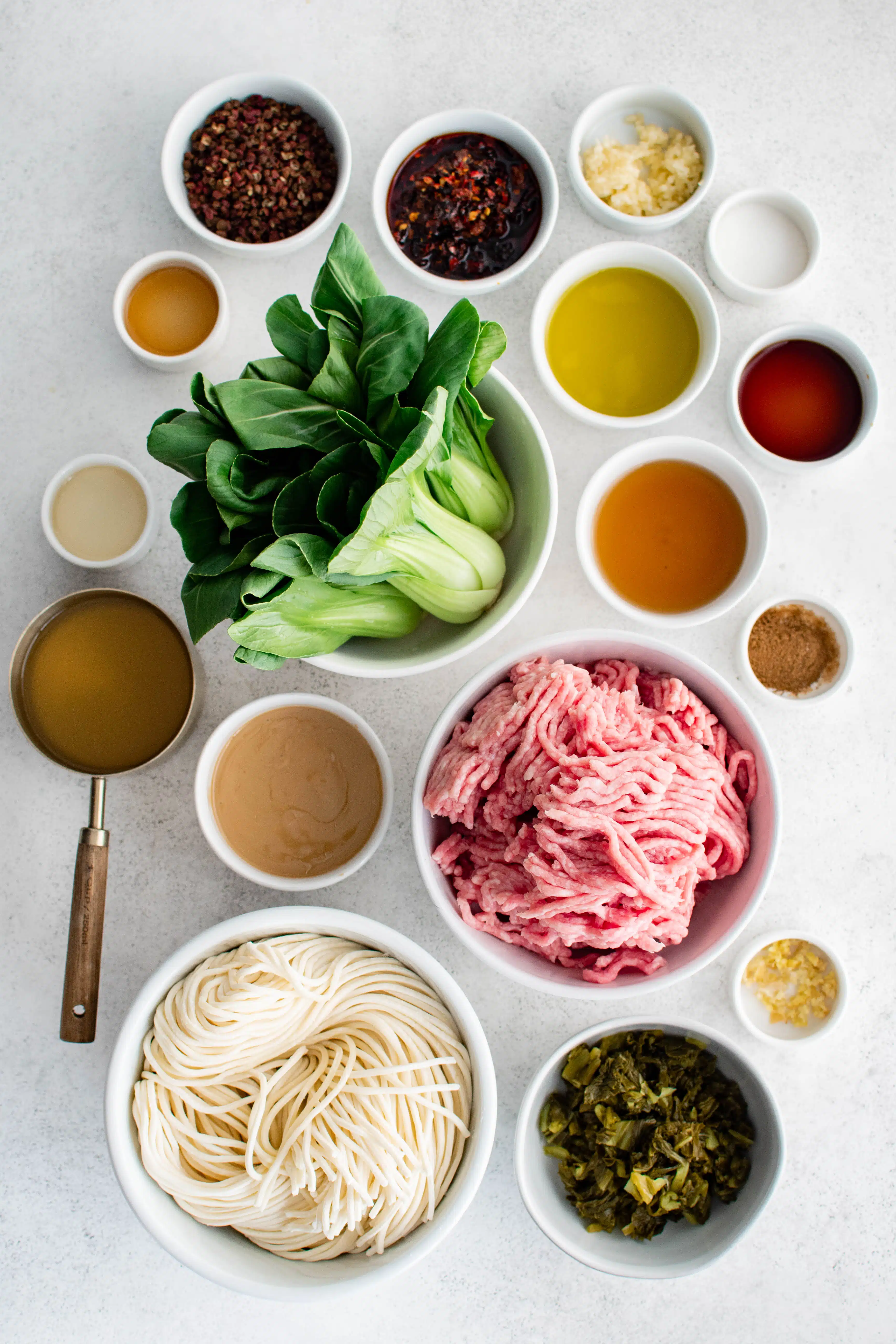 Ingredients needed to make dan dan noodles in individual measuring cups and ramekins.